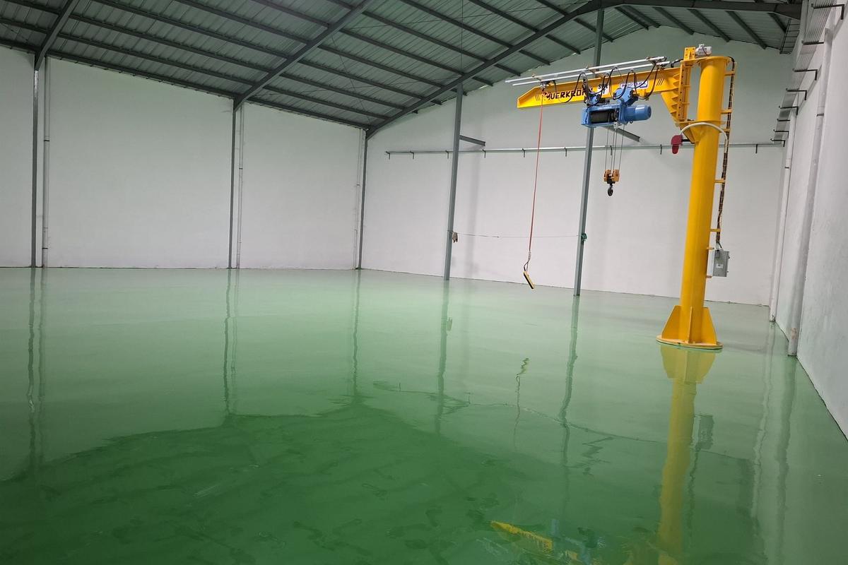 Lantai epoxy hijau di bawah jib crane kuning pada pabrik Daeshin Flange Fitting Industri