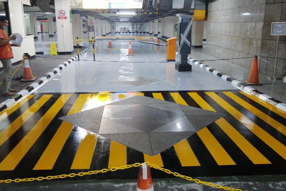 Marka chevron hitam kuning mengelilingi tugu granit di lantai parkir Jakarta Stock Exchange