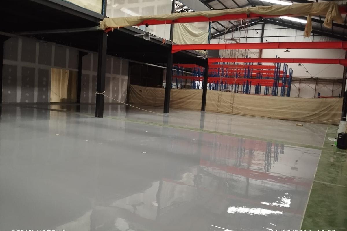 Gudang Milenia Mega Mandiri dengan lantai epoxy abu-abu di antara kolom baja merah