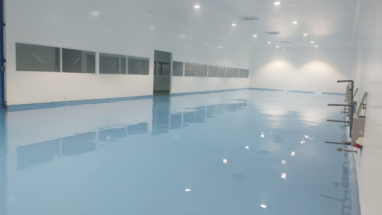 Ruang produksi Agarindo dengan lantai epoxy biru muda dan saluran air di tengah ruang