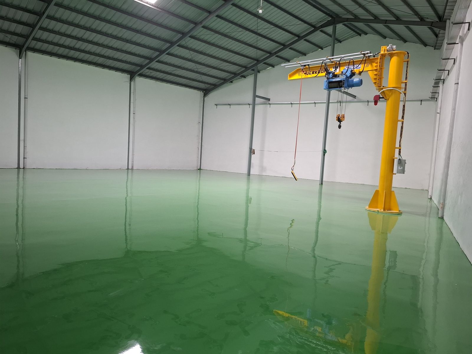 Lantai epoxy hijau di bawah jib crane kuning pada pabrik Daeshin Flange Fitting Industri
