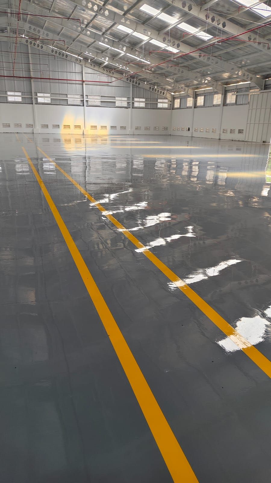 Gudang Dahana dengan lantai epoxy abu-abu dan marka jalur kuning memanjang (2/2)