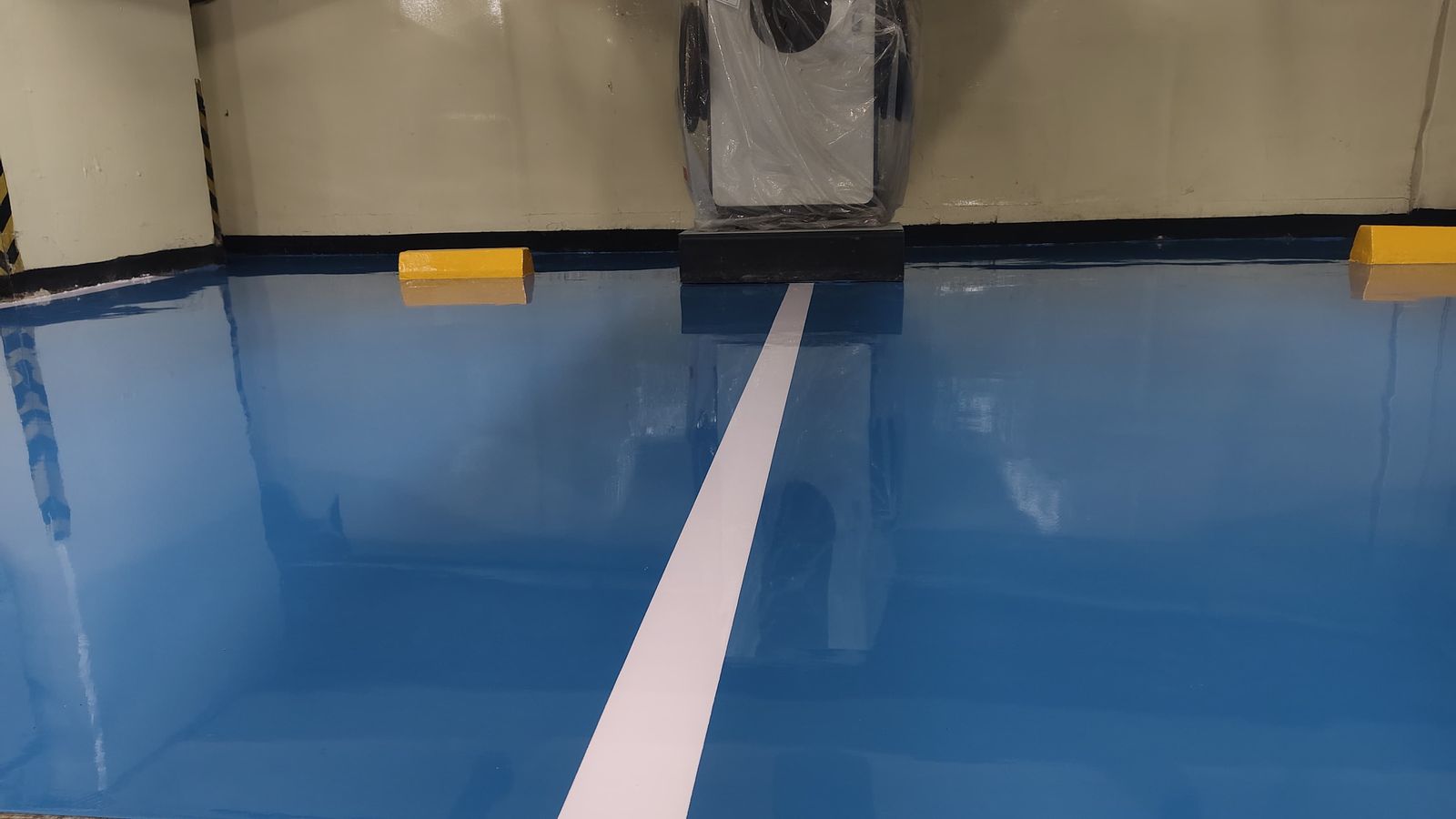 Lantai epoxy biru dengan marka jalur putih di area servis PT Deqha