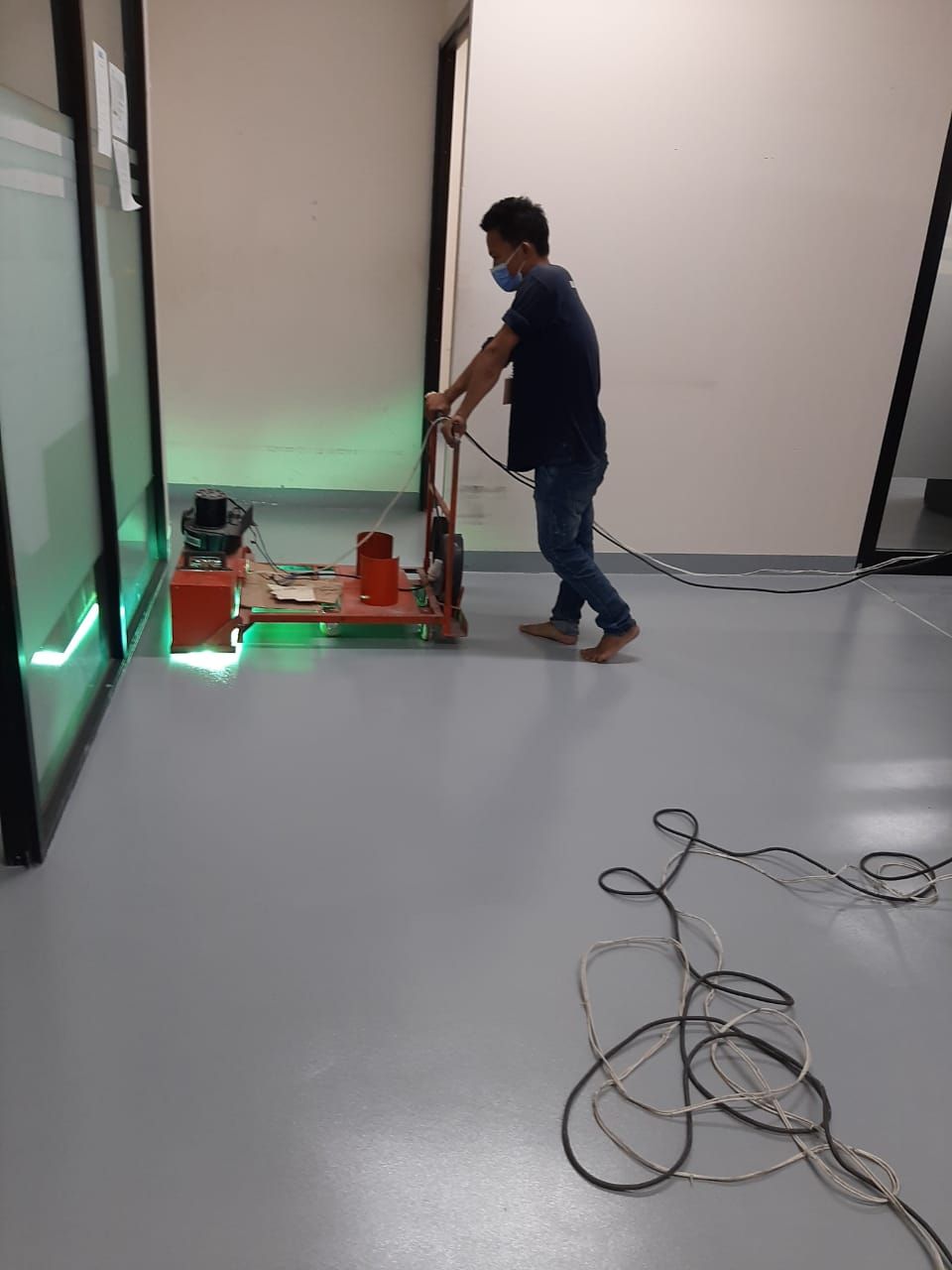 Aplikator memoles lantai epoxy abu-abu di koridor servis Fairmont Jakarta (2/3)