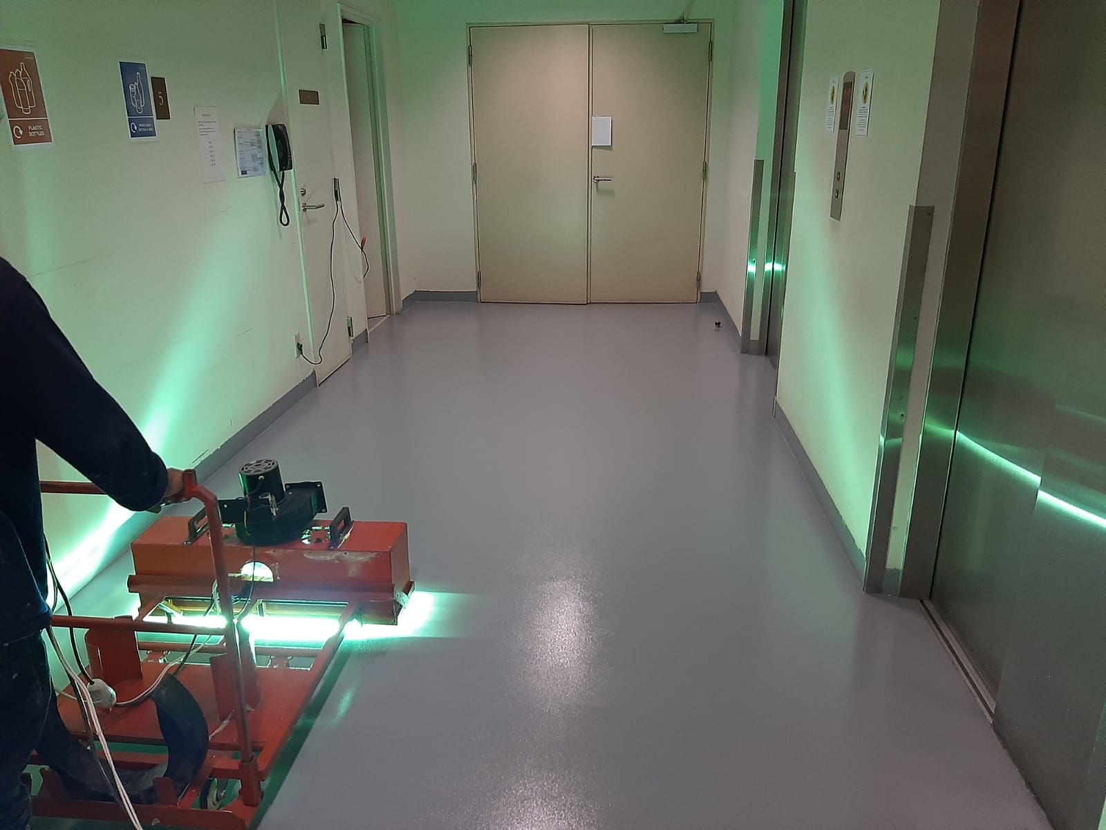 Aplikator memoles lantai epoxy abu-abu di koridor servis Fairmont Jakarta