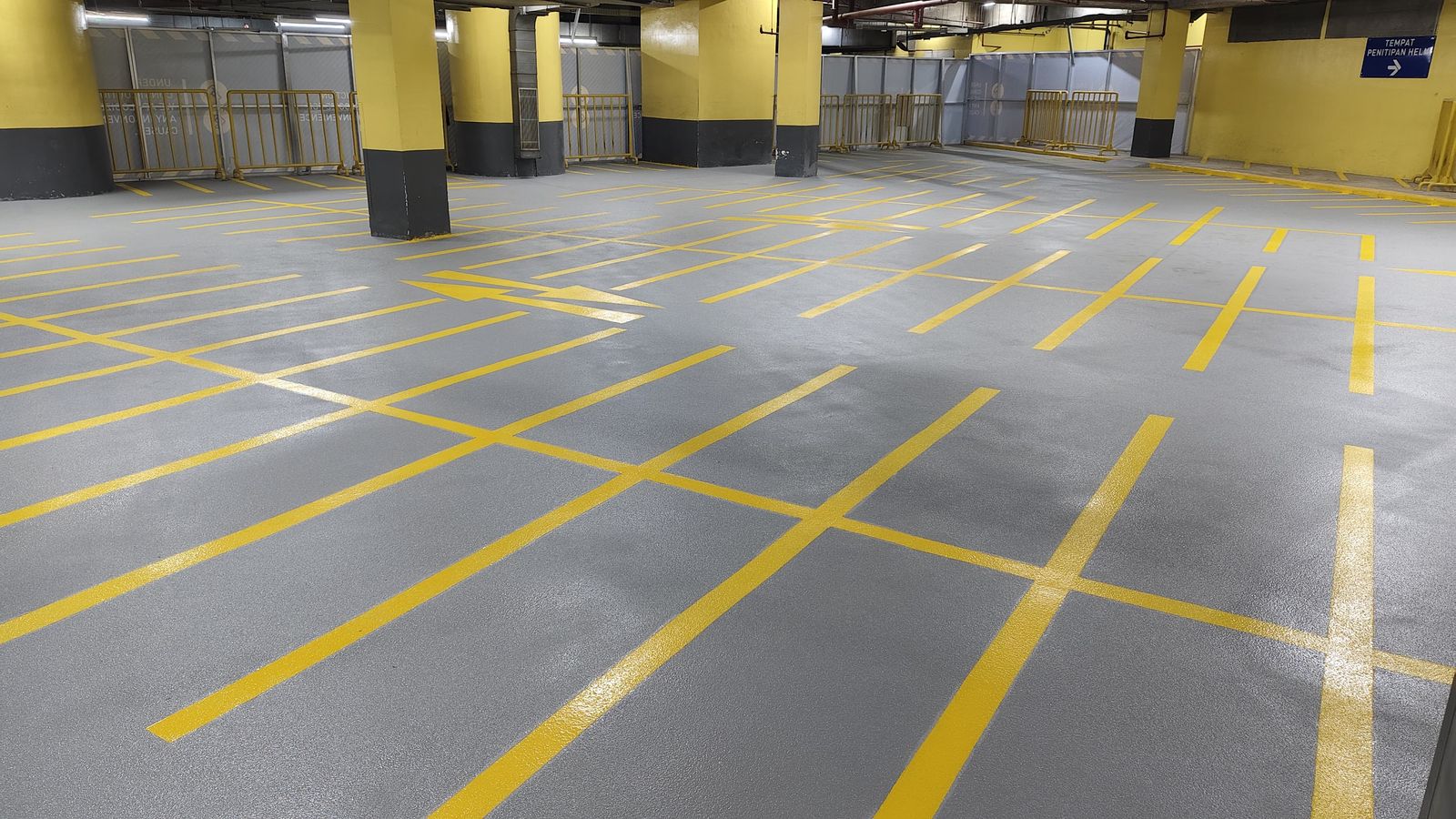 Basement parkir Grand Indonesia dengan grid marka kuning dan kolom bercat kuning