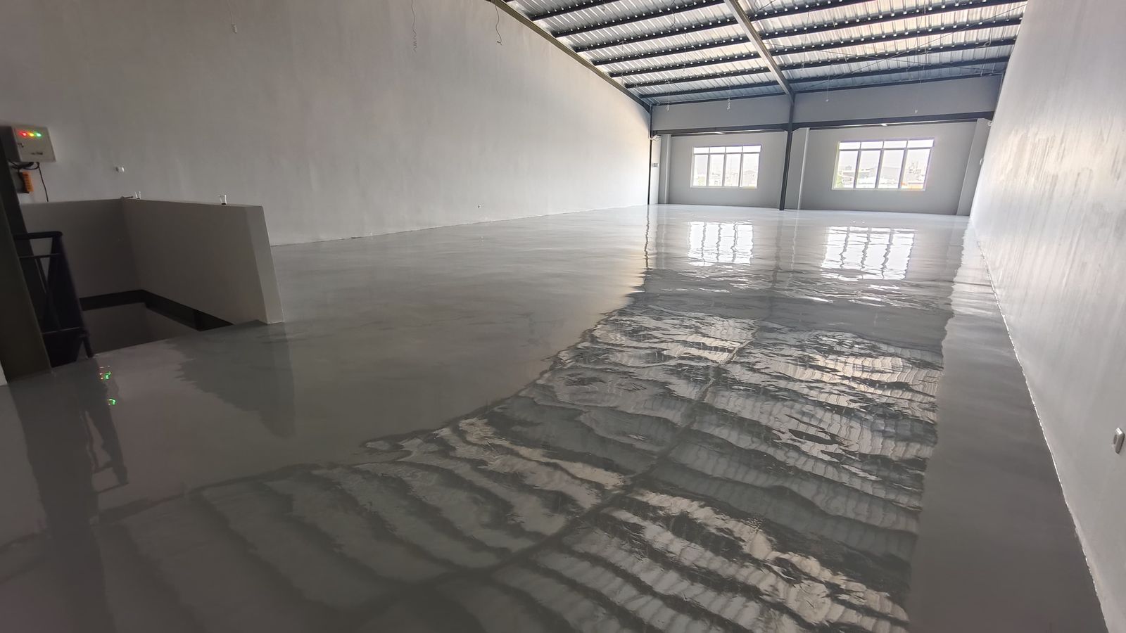 Ruang produksi Inti Berkat Jaya dengan lantai epoxy abu-abu muda dan rangka baja terbuka