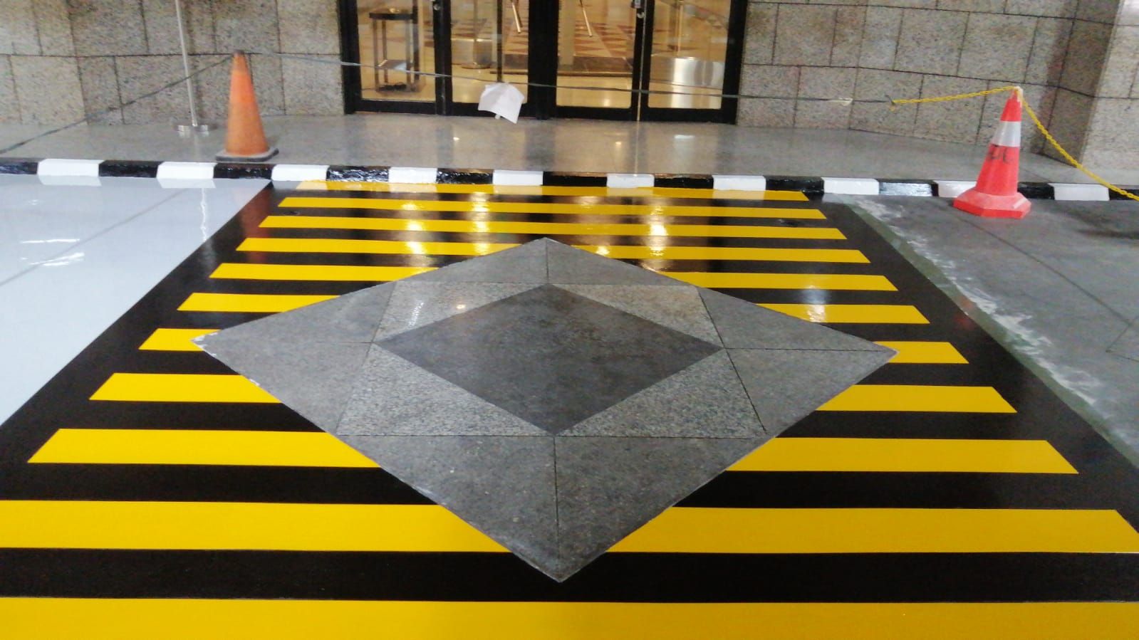 Marka chevron hitam kuning mengelilingi tugu granit di lantai parkir Jakarta Stock Exchange (4/8)