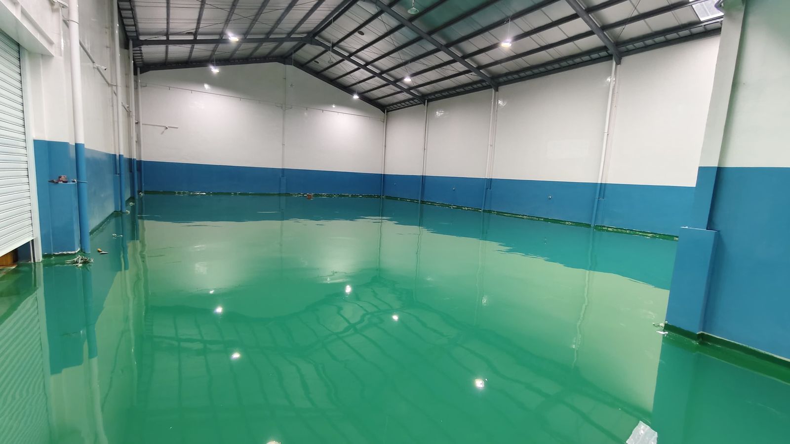 Lantai epoxy hijau dengan dinding biru di ruang produksi Jaya Kreasi