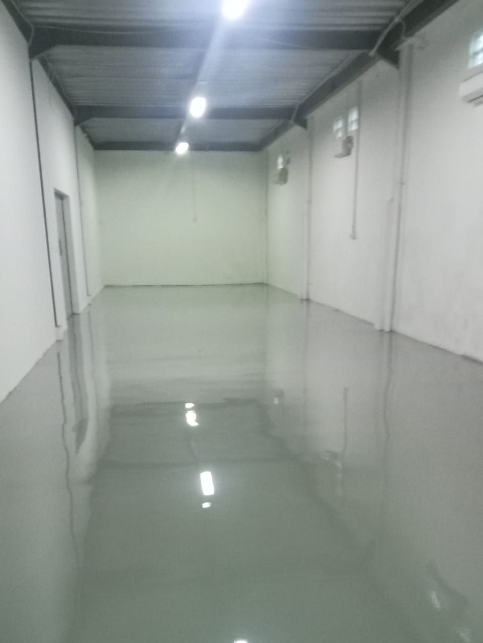 Koridor penyimpanan Juva Beauty Indonesia dengan lantai epoxy abu-abu muda dan rak biru (2/4)