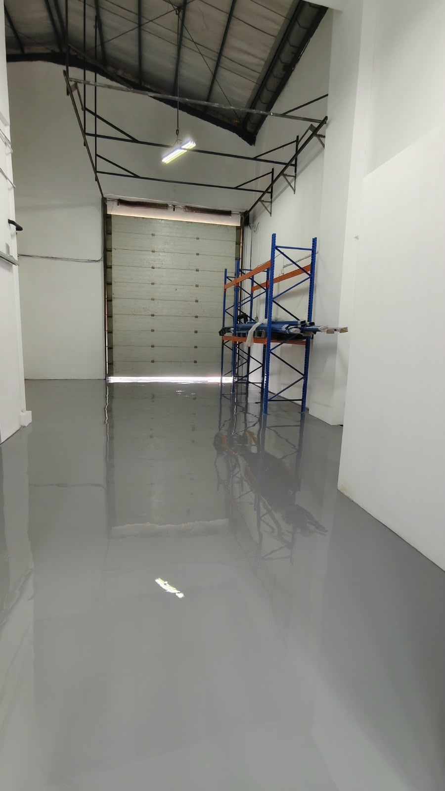 Koridor penyimpanan Juva Beauty Indonesia dengan lantai epoxy abu-abu muda dan rak biru (3/4)