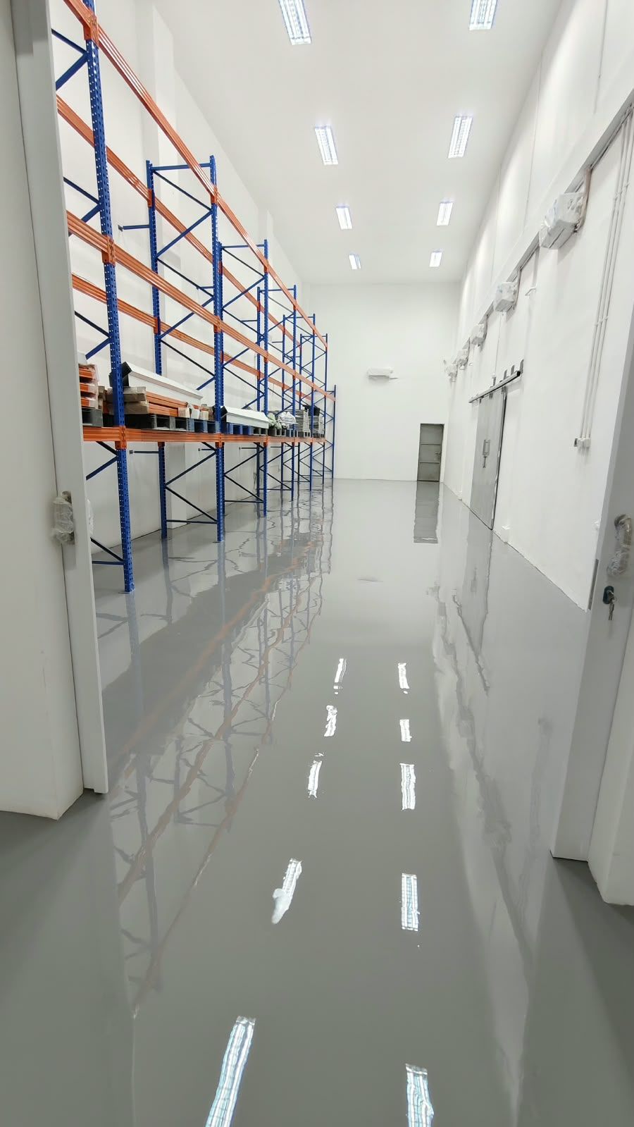 Koridor penyimpanan Juva Beauty Indonesia dengan lantai epoxy abu-abu muda dan rak biru