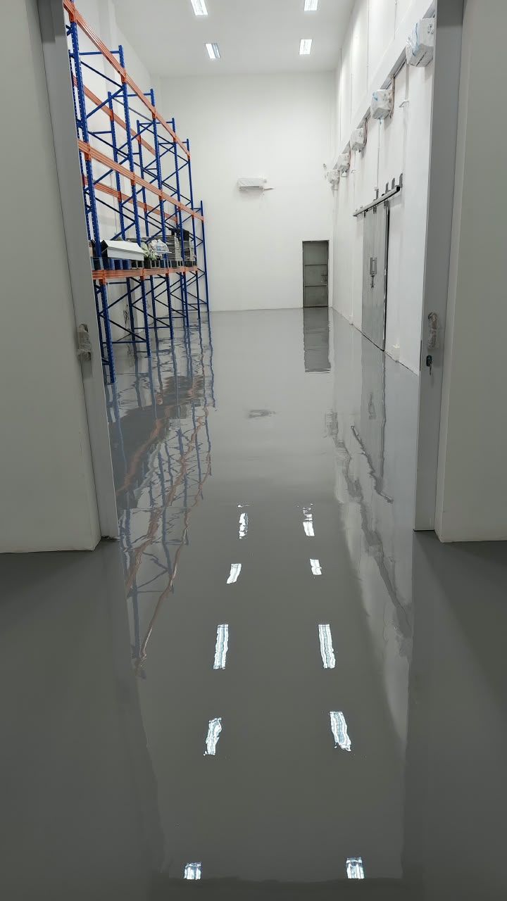 Koridor penyimpanan Juva Beauty Indonesia dengan lantai epoxy abu-abu muda dan rak biru (4/4)