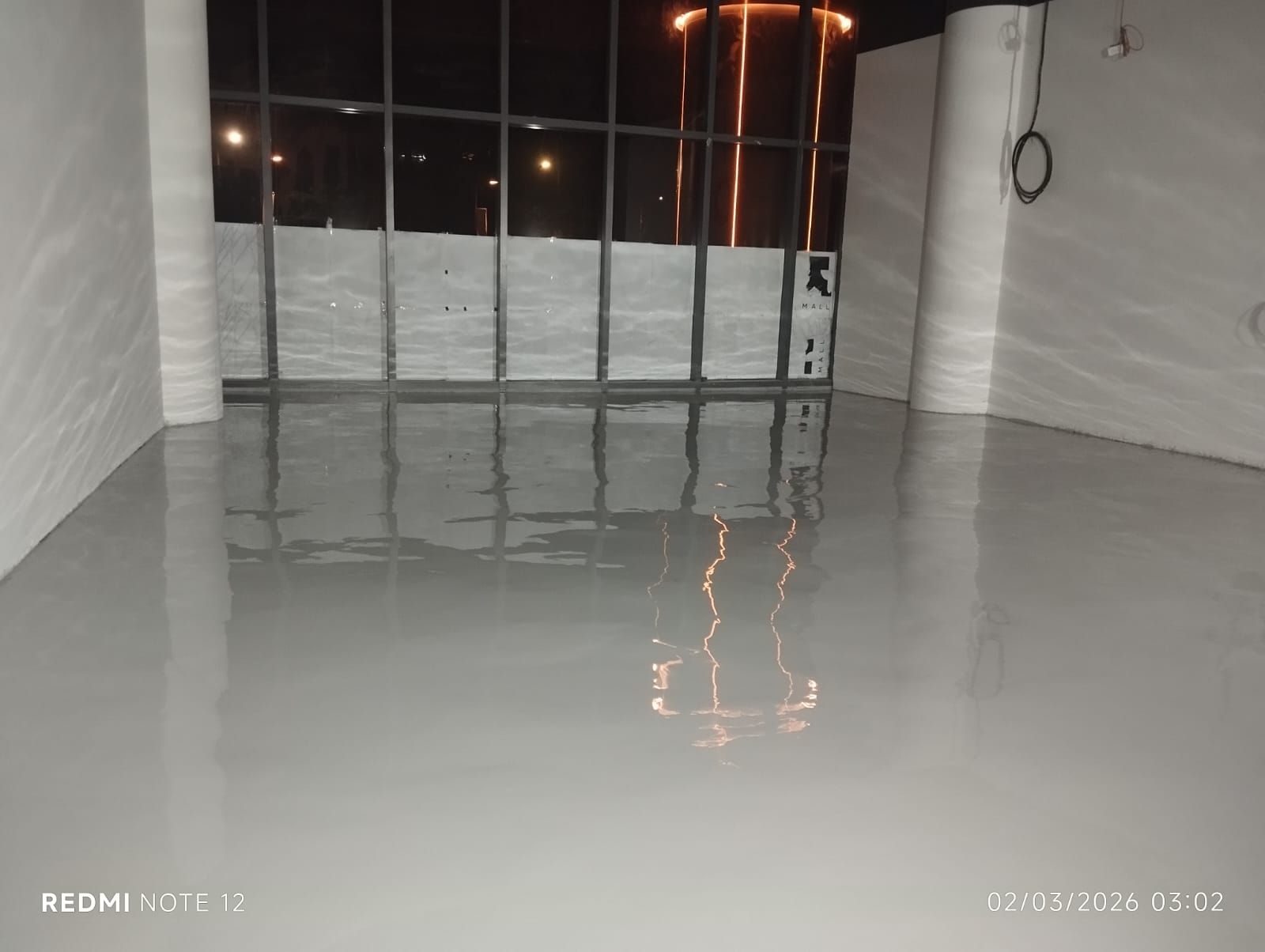Lantai parkir K Mall dengan epoxy abu-abu di antara kolom beton