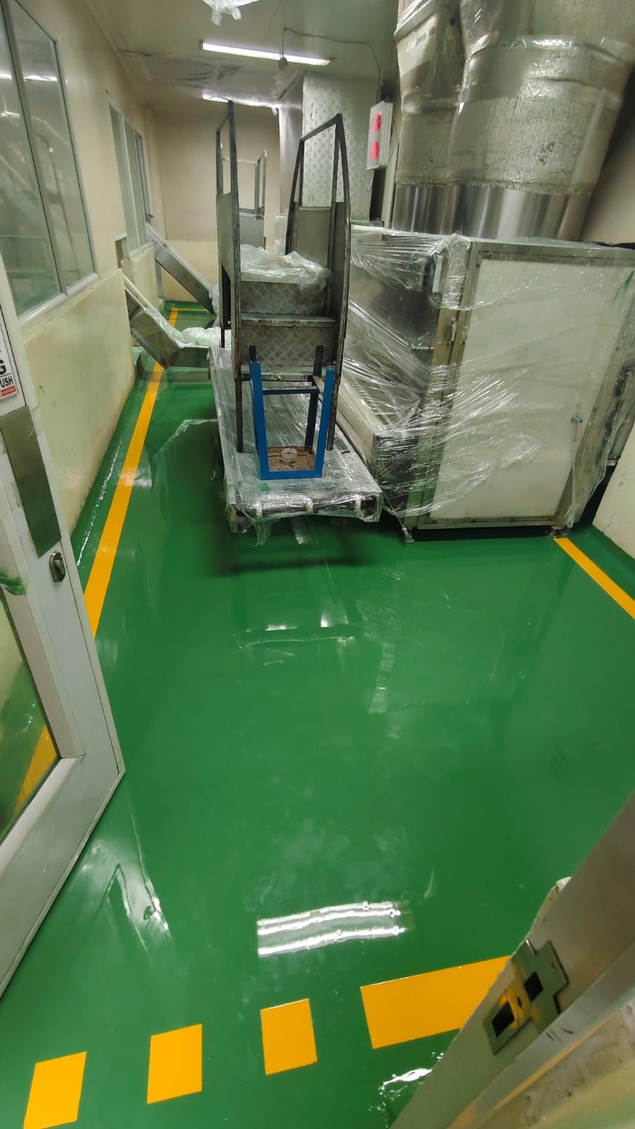 Koridor pabrik Mayora dengan lantai epoxy hijau dan garis jalur kuning di kedua sisi (2/8)