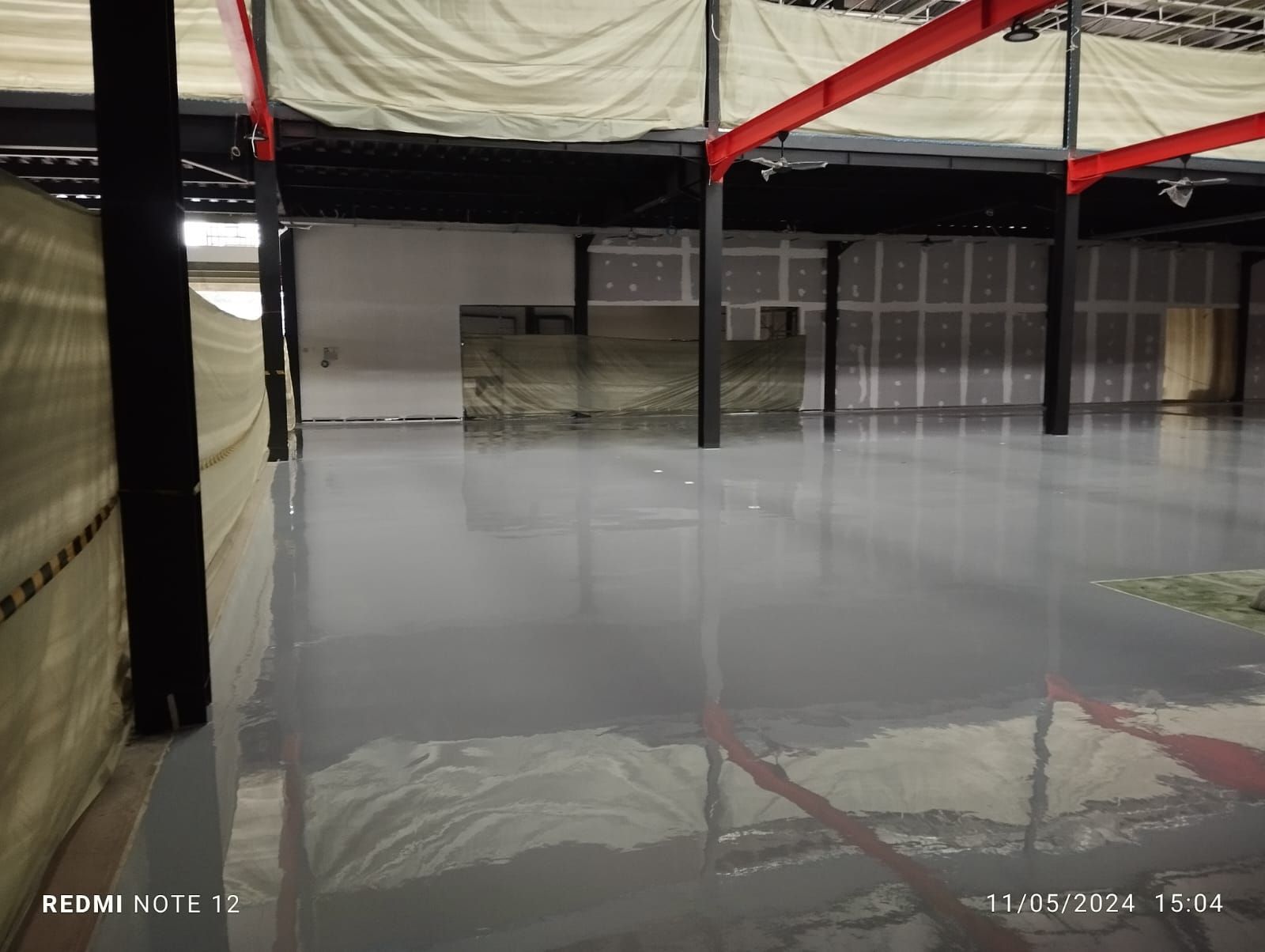 Gudang Milenia Mega Mandiri dengan lantai epoxy abu-abu di antara kolom baja merah (3/3)