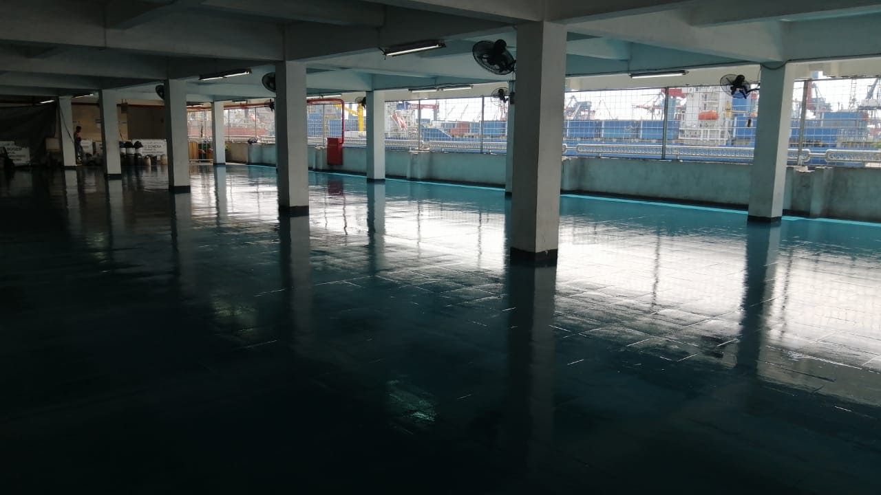 Lantai epoxy biru di gudang Pelindo Tanjung Priok, memanjang di antara deretan kolom (2/6)