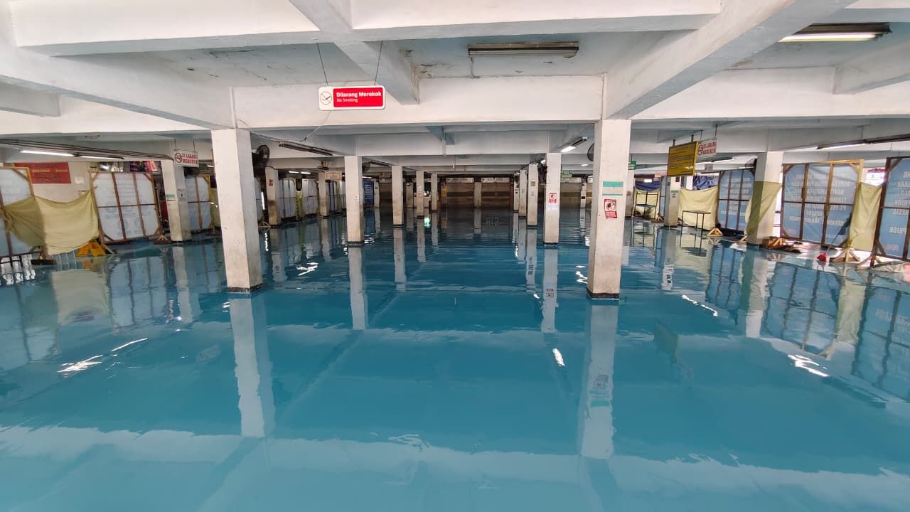 Lantai epoxy biru di gudang Pelindo Tanjung Priok, memanjang di antara deretan kolom