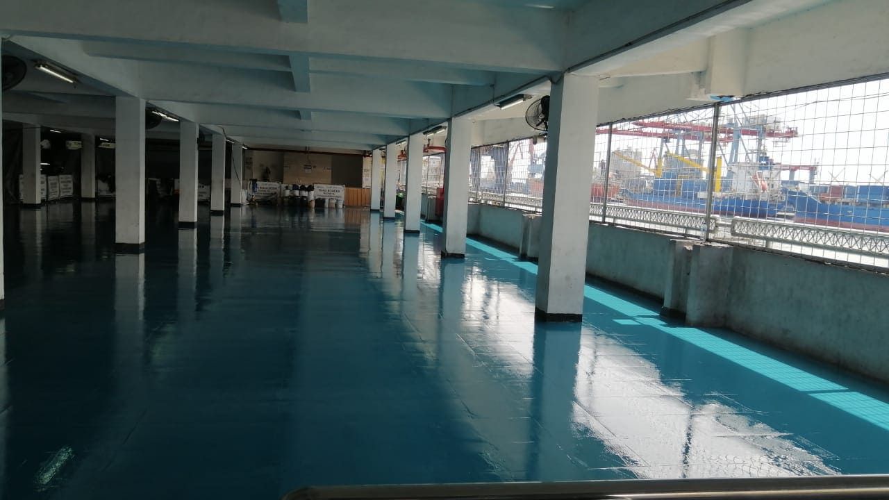 Lantai epoxy biru di gudang Pelindo Tanjung Priok, memanjang di antara deretan kolom (4/6)