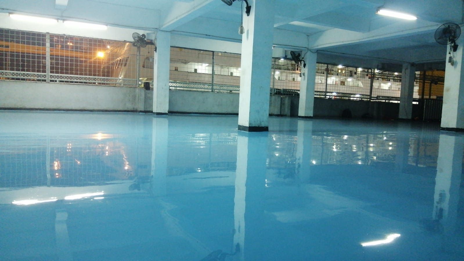 Lantai epoxy biru di gudang Pelindo Tanjung Priok, memanjang di antara deretan kolom (6/6)