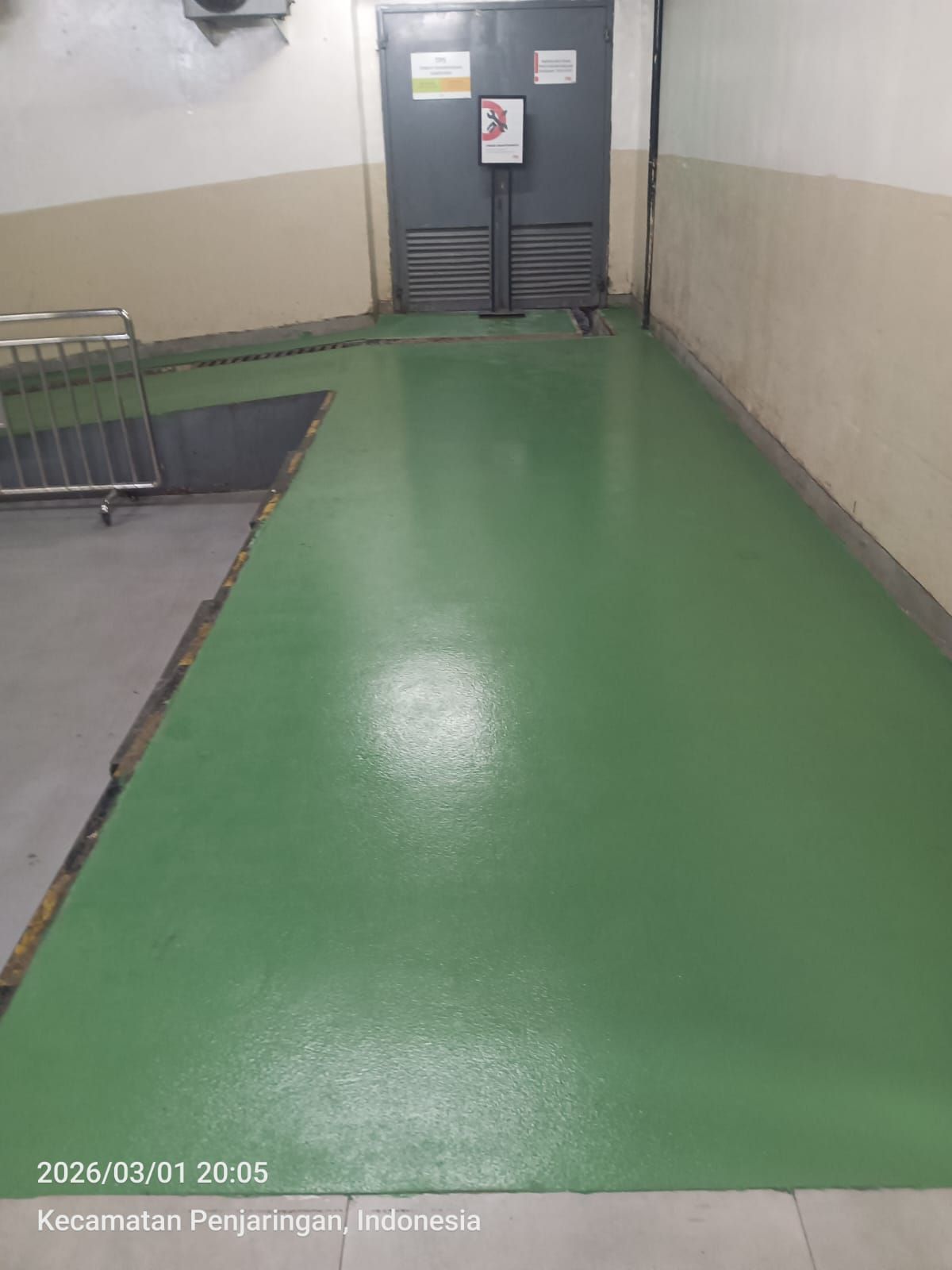 Ramp parkir PIK Avenue dengan lantai epoxy hijau dan marka kuning