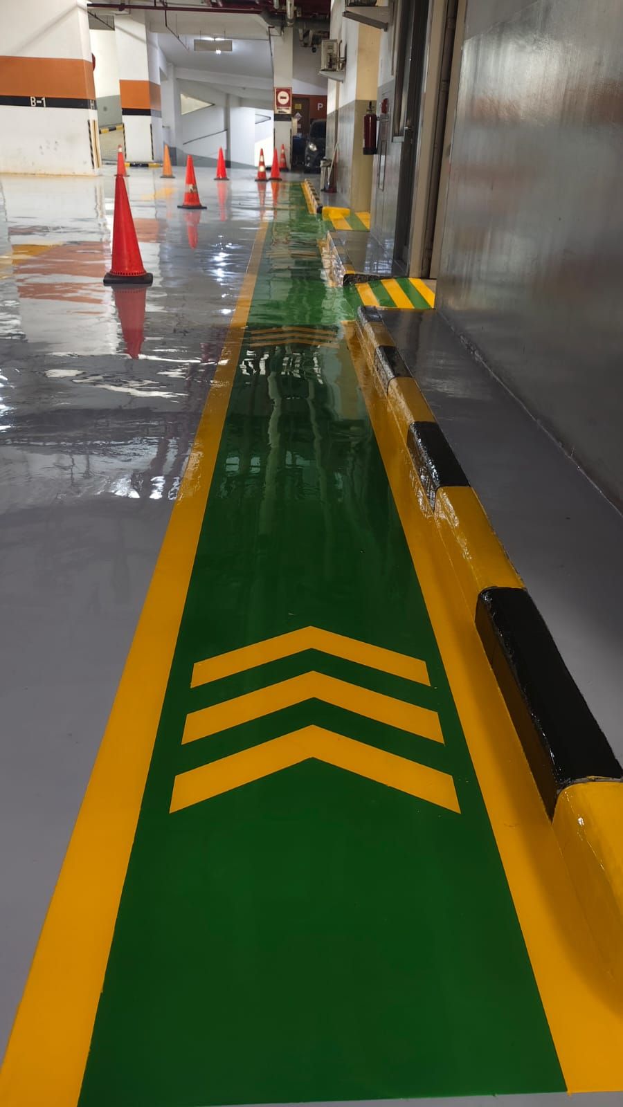 Basement parkir Plaza BPJAMSOSTEK dengan lantai epoxy abu-abu dan kolom bermarka oranye (5/5)