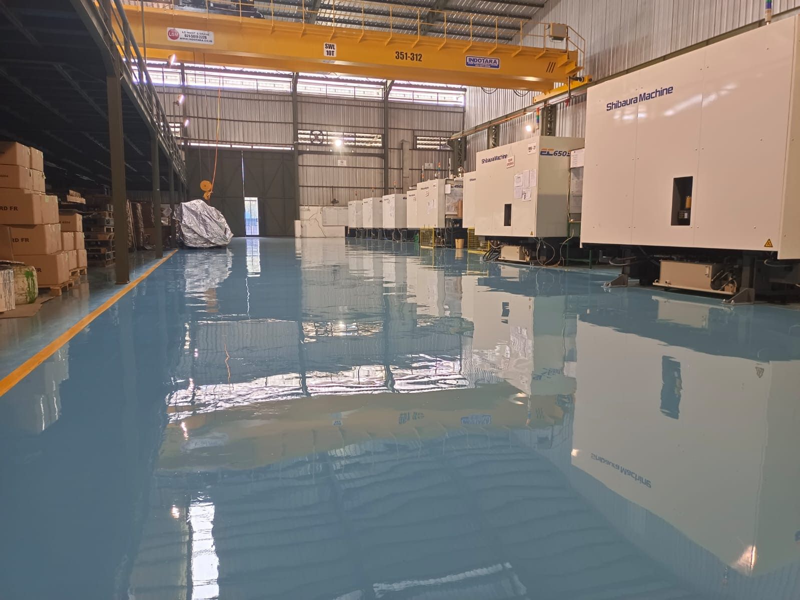 Area produksi Prima Komponen dengan lantai epoxy biru muda dan mesin di sepanjang dinding