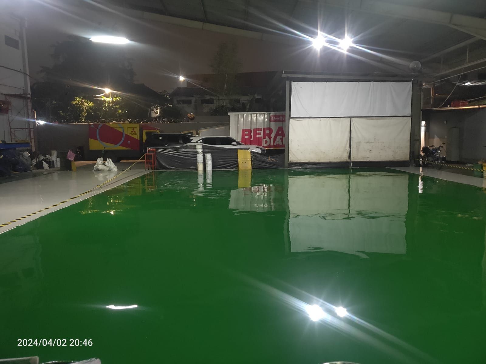 Area servis PT Salindo Berlian Motor dengan lantai epoxy hijau dan truk di atas dongkrak (2/4)