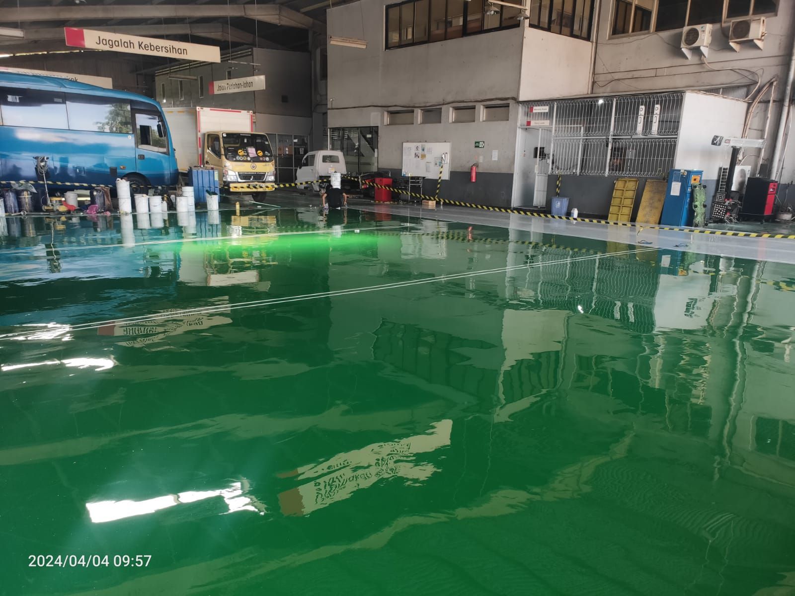 Area servis PT Salindo Berlian Motor dengan lantai epoxy hijau dan truk di atas dongkrak