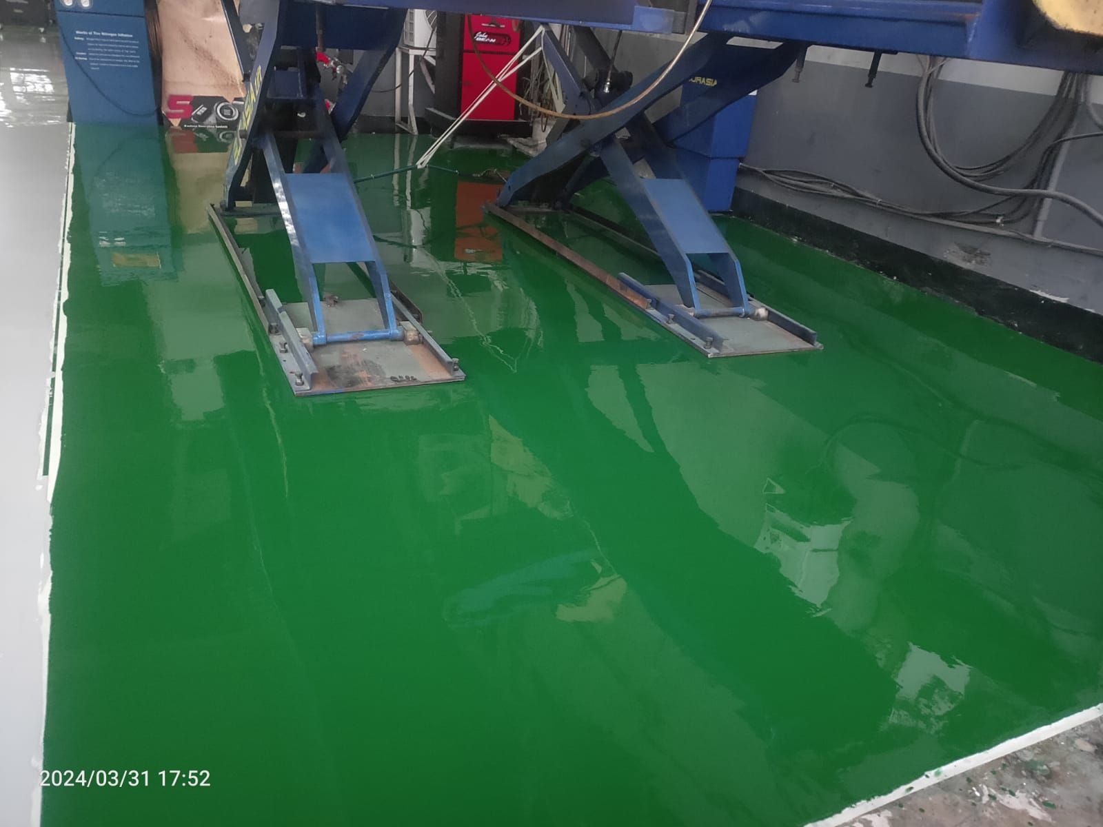 Area servis PT Salindo Berlian Motor dengan lantai epoxy hijau dan truk di atas dongkrak (3/4)