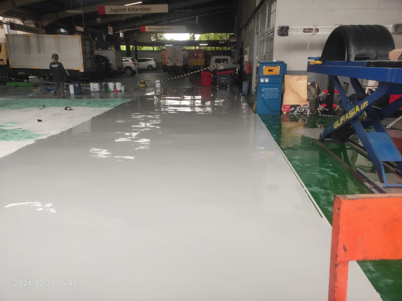 Area servis PT Salindo Berlian Motor dengan lantai epoxy hijau dan truk di atas dongkrak (4/4)