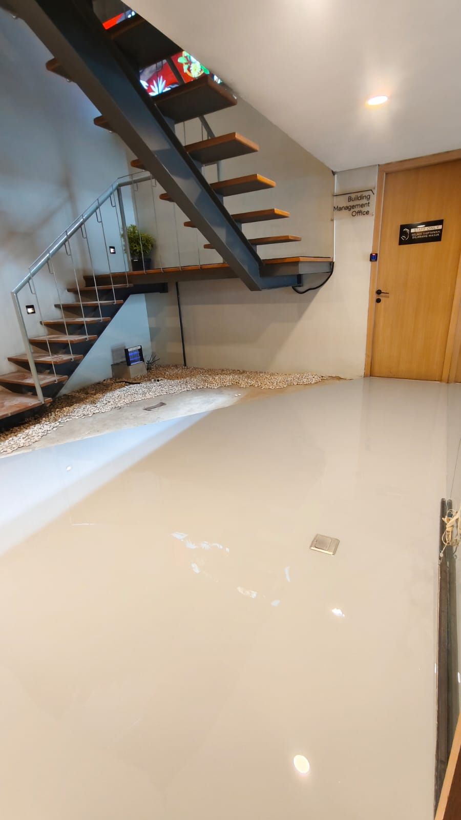 Studio Shooting Star dengan lantai epoxy krem mengilap dan tangga di sudut ruang