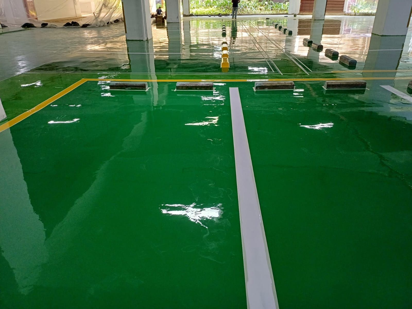Basement parkir Springhill Royale Suites dengan lantai epoxy hijau dan marka jalur putih