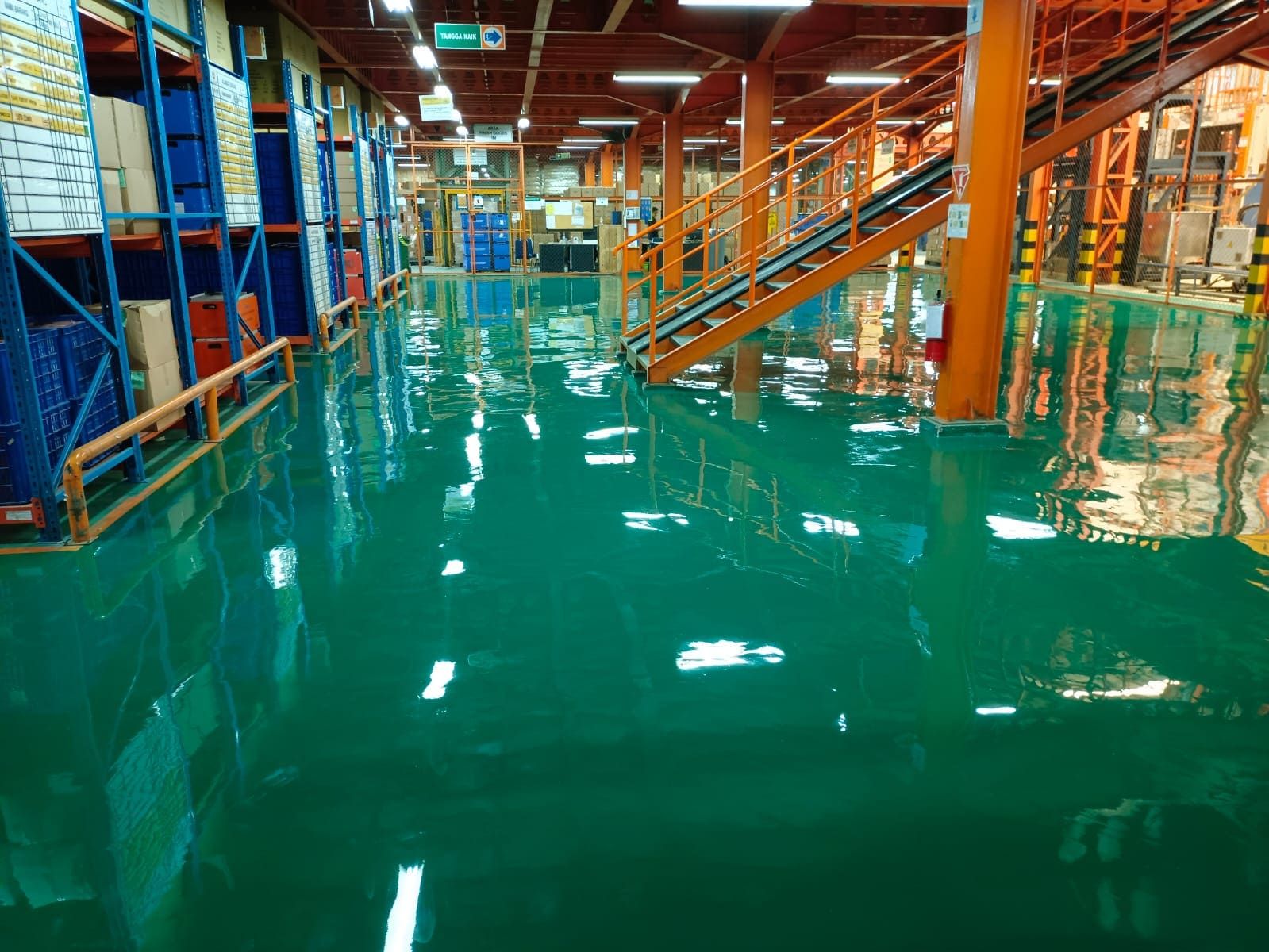 Lantai epoxy hijau di antara kolom oranye pada pabrik Terang Parts Indonesia