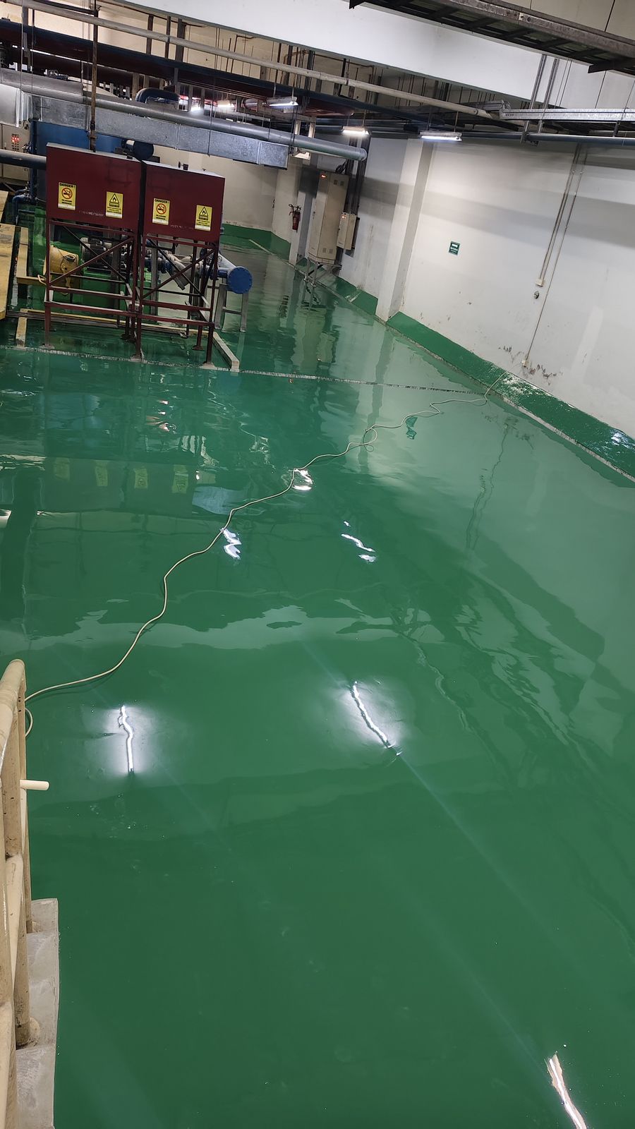 Ruang pompa Thamrin Residences dengan lantai epoxy hijau di bawah jaringan pipa (2/3)