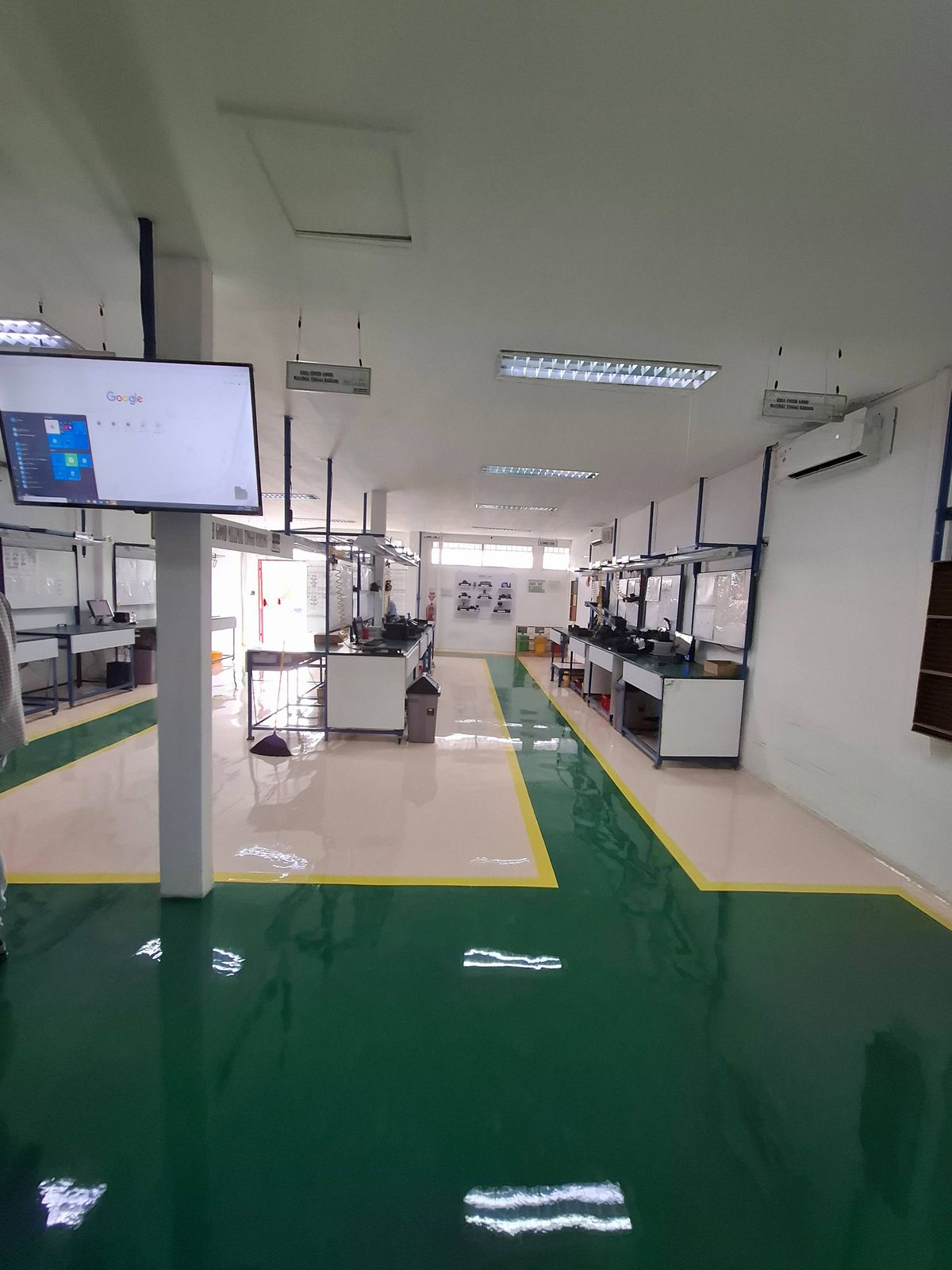 Lantai epoxy putih dengan zona hijau dan marka kuning di ruang perakitan Vega Mandiri (2/9)