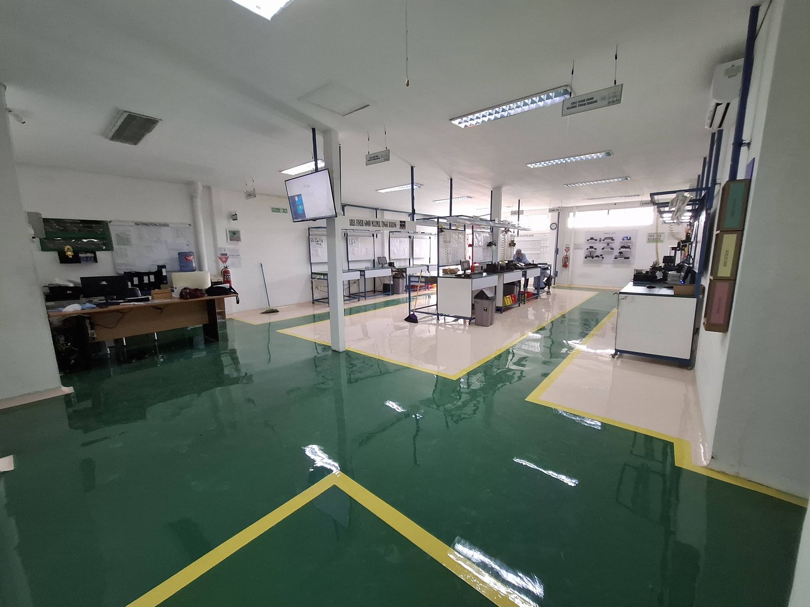 Lantai epoxy putih dengan zona hijau dan marka kuning di ruang perakitan Vega Mandiri