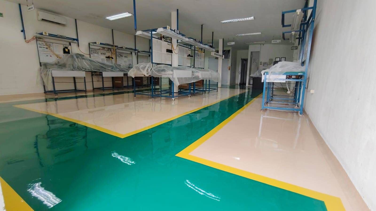 Lantai epoxy putih dengan zona hijau dan marka kuning di ruang perakitan Vega Mandiri (3/9)