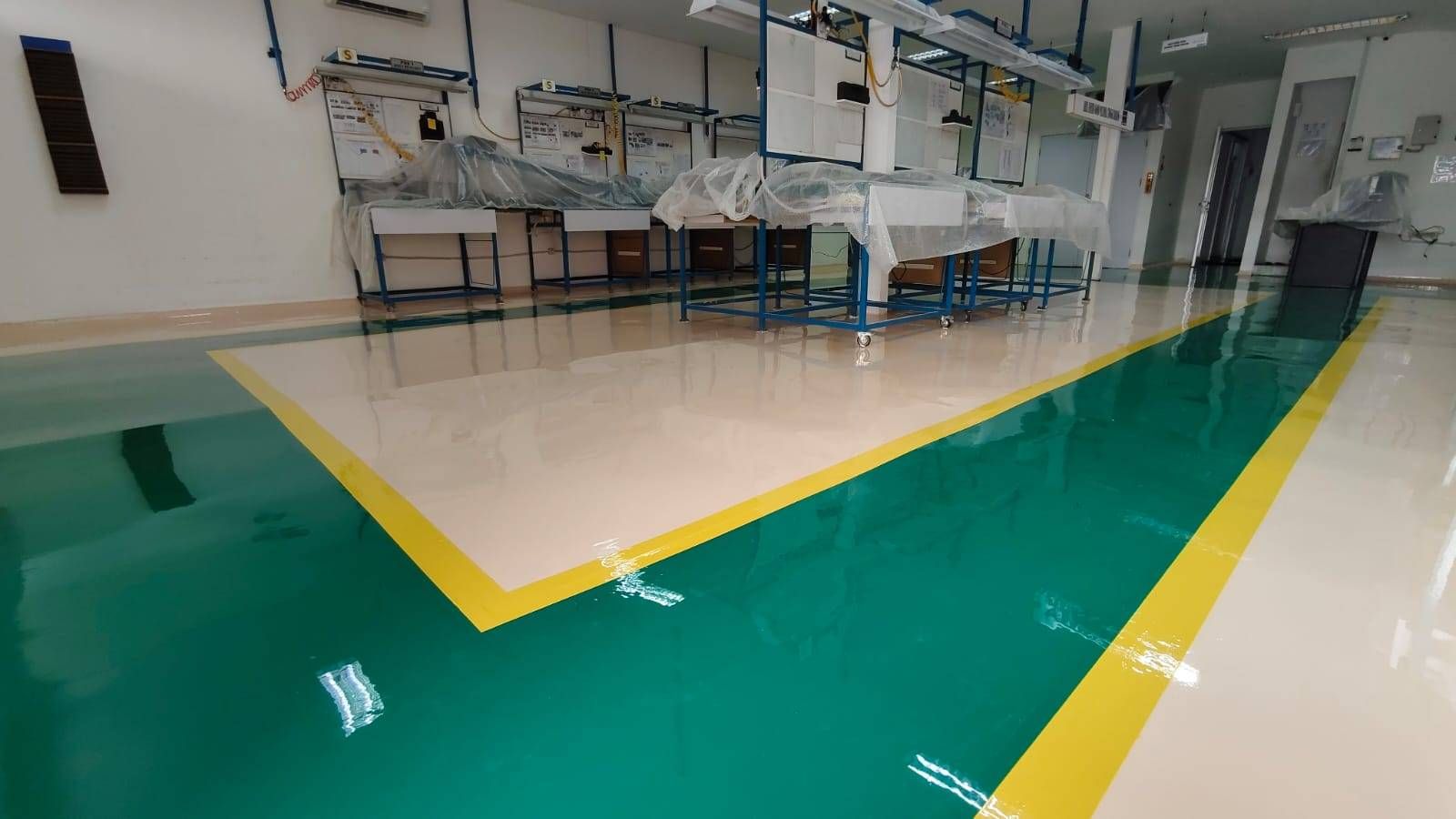 Lantai epoxy putih dengan zona hijau dan marka kuning di ruang perakitan Vega Mandiri (4/9)