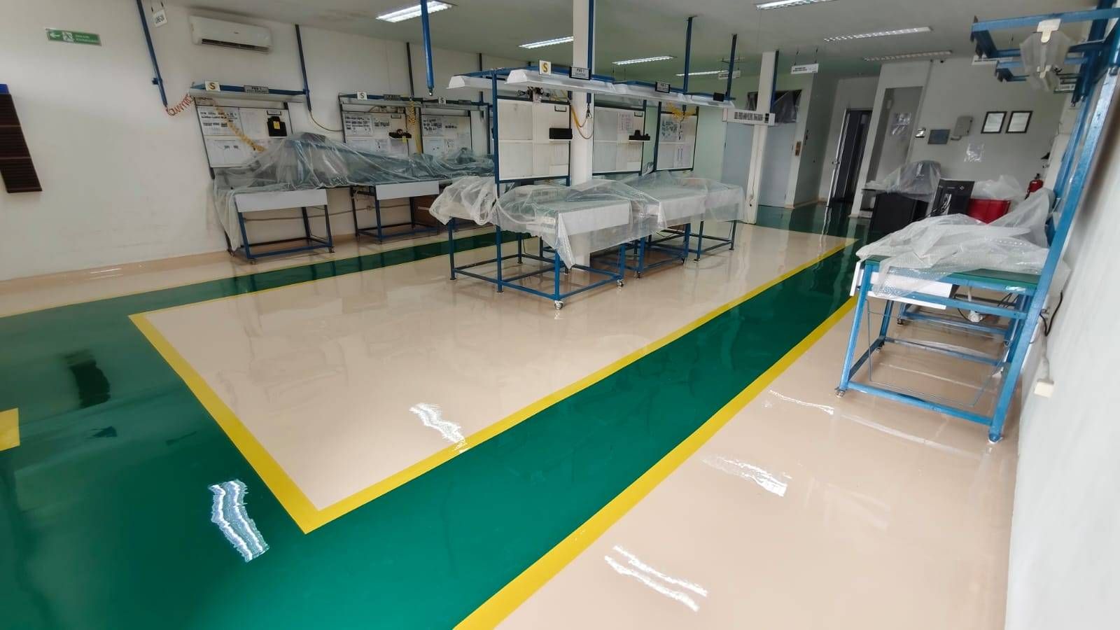 Lantai epoxy putih dengan zona hijau dan marka kuning di ruang perakitan Vega Mandiri (5/9)