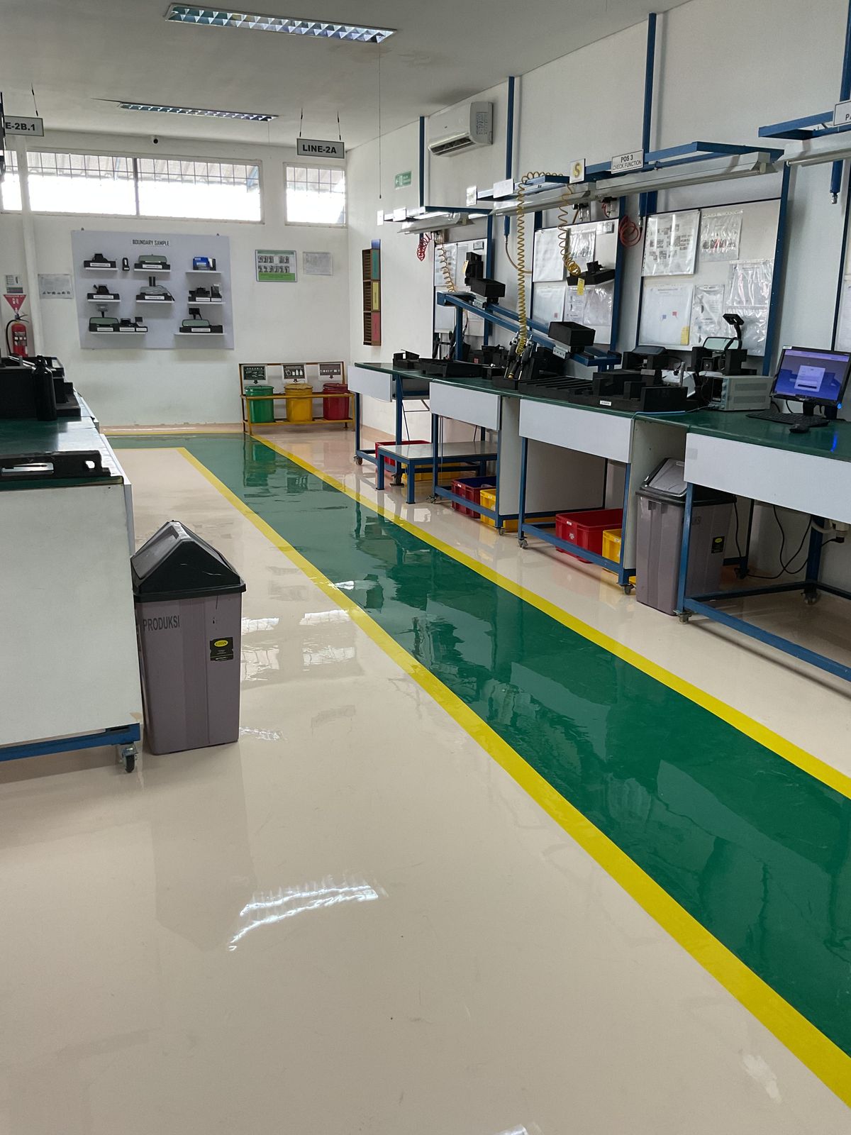 Lantai epoxy putih dengan zona hijau dan marka kuning di ruang perakitan Vega Mandiri (7/9)