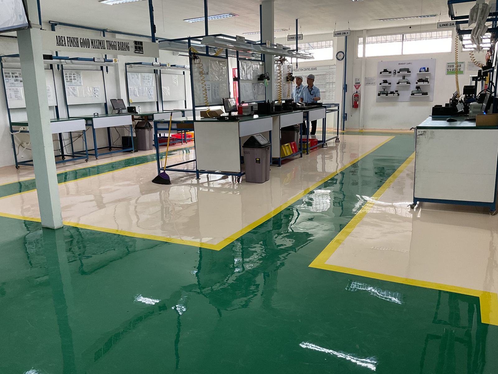 Lantai epoxy putih dengan zona hijau dan marka kuning di ruang perakitan Vega Mandiri (8/9)