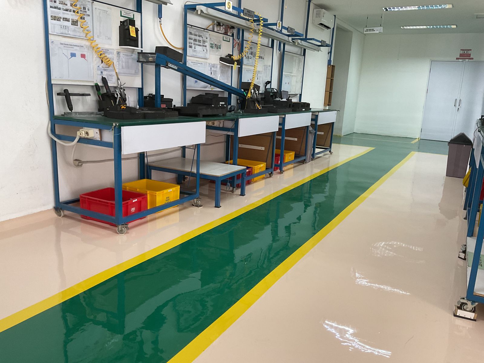 Lantai epoxy putih dengan zona hijau dan marka kuning di ruang perakitan Vega Mandiri (9/9)